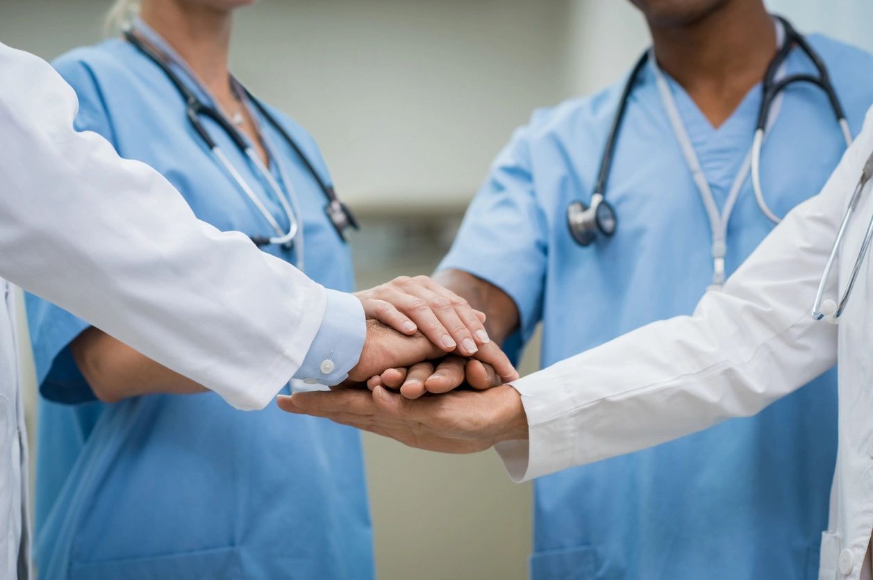 Two doctors holding hands with each other in a circle.